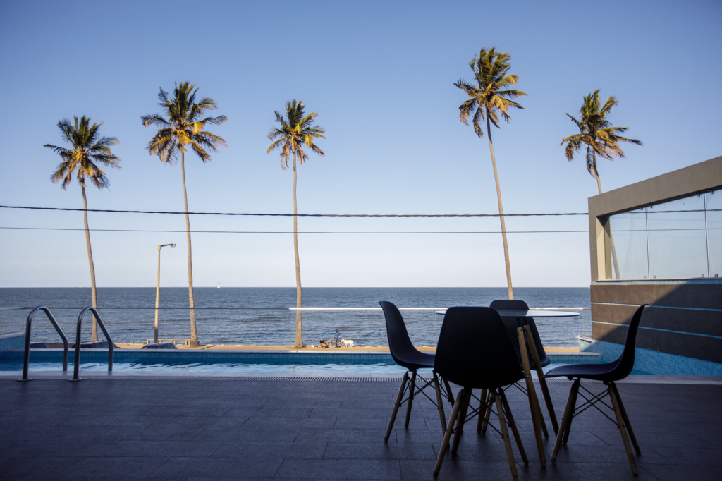 Piscina das CoWork Lab Suites em Maputo, com palmeiras e vista sobre a baía